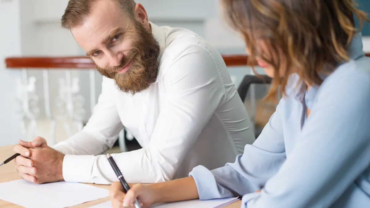 Dos personas conversando y tomando notas durante una reunión de trabajo